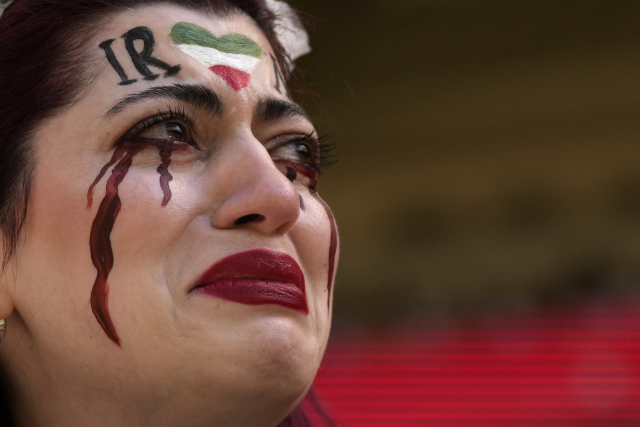 한 이란 여성이 자신의 얼굴에 이란 국기와 검은 피눈물을 그려 넣고 25일(현지시간) 카타르에서 열린 웨일스 대 이란 경기를 관람하고 있다. /AP연합뉴스