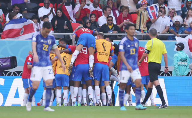 27일 카타르 월드컵 E조 2차전에서 선제골을 넣고 환호하는 코스타리카 선수들 뒤로 일본 선수들이 허탈한 표정을 짓고 있다. 연합뉴스