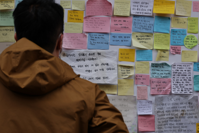 시민이 28일 오후 서울 용산구 이태원동 사고 현장에서 시민들의 추모 글을 읽고 있다. 연합뉴스