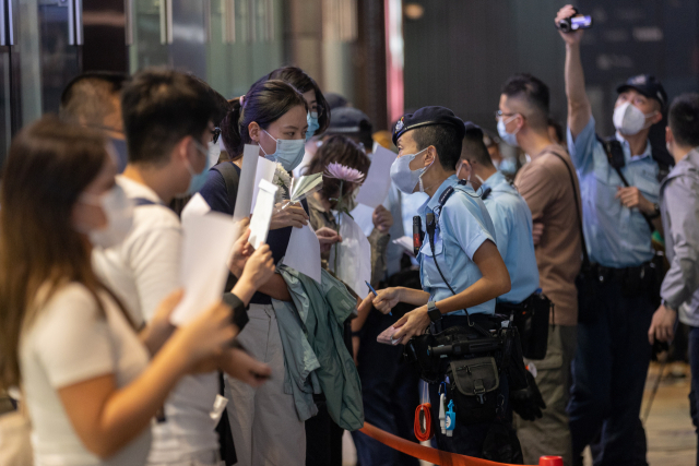 28일(현지시간) 홍콩에서 열린 중국 우루무치 화재 희생자 추모집회에서 경찰이 시위 참가자들의 신분증을 검사하고 있다. 연합뉴스