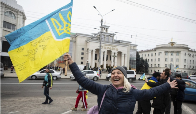 12일(현지시간) 우크라이나 헤르손 시내에서 주민들이 우크라이나 국장이 그려진 깃발을 들고 탈환을 축하하고 있다. 연합뉴스 캡처