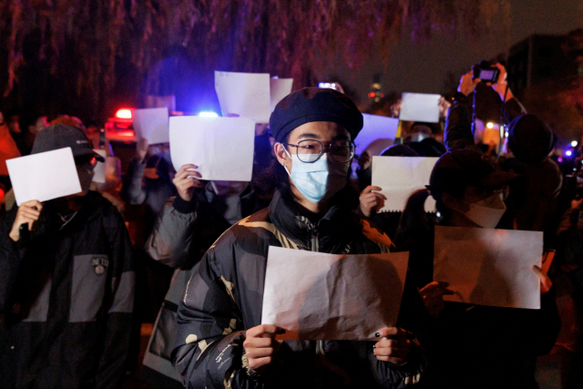 27일 중국 베이징에서 열린 우루무치 화재 희생자 추도식에서 코로나19 봉쇄 조치에 반대하는 시민들이 검열에 대한 저항의 상징으로 '백지 시위'를 펼치고 있다. 로이터연합뉴스