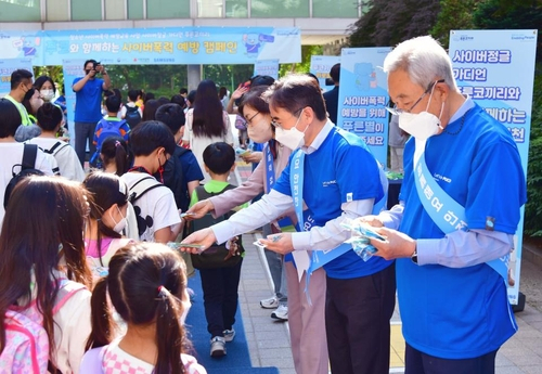 장덕현(오른쪽 두 번째) 삼성전기 대표가 서울 성북구 매원초등학교 정문에서 등교하는 학생들에게 사이버 폭력 근절 팸플릿 및 기념품을 전달하고 있다. 사진 제공=삼성전기