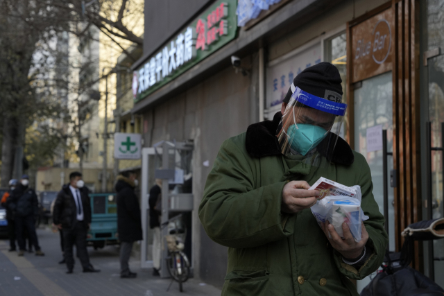 9일(현지시간) 중국 베이징의 한 약국 앞에 시민들이 줄을 서있는 가운데 한 남성이 자신이 구입한 약을 살펴보고 있다. 연합뉴스