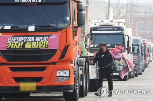 화물연대가 파업을 종료하고 현장 복귀를 결정한 9일 오후 경기도 의왕시 내륙컨테이너기지(ICD) 앞에서 관계자가 도로에 세워둔 화물차들에 붙어있던 파업 관련 현수막을 철거하고 있다. 연합뉴스