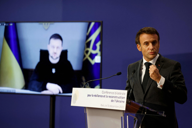 에마뉘엘 마크롱(오른쪽) 프랑스 대통령이 13일(현지 시간) 프랑스 파리에서 열린 우크라이나 지원 국제회의에서 발언하고 있는 가운데 왼쪽 TV 화면을 통해 화상으로 참석한 볼로디미르 젤렌스키 우크라이나 대통령의 모습이 보이고 있다. AFP연합뉴스