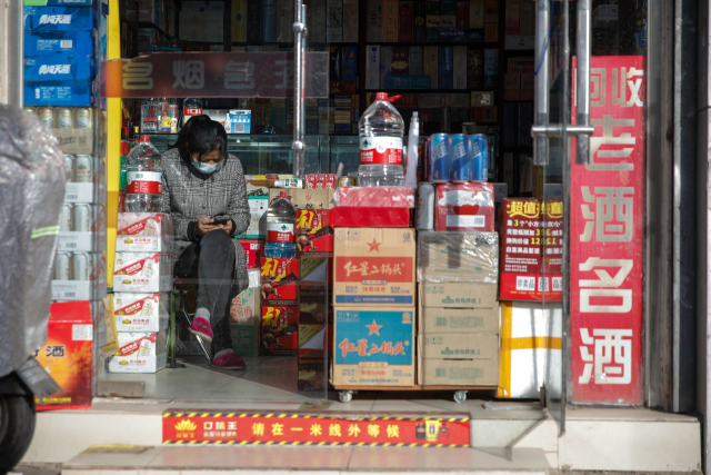 마스크를 쓴 여성 점원이 15일 베이징의 한 슈퍼에서 휴대전화를 들여다 보고 있다. 중국의 11월 소매 판매는 전년 동기 대비 5.9% 감소하며 급격한 소비 위축세를 나타냈다. EPA연합뉴스.