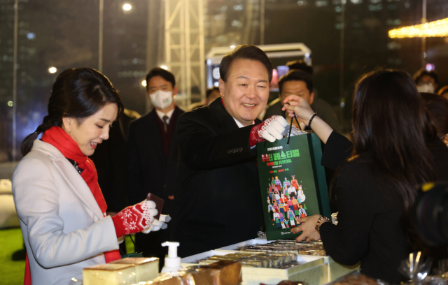 윤석열 대통령과 김건희 여사가 16일 오후 서울 종로구 열린송현광장에서 열린 윈·윈터 페스티벌 개막식에서 에어돔 부스를 방문, 물건을 구입하고 있다./연합뉴스