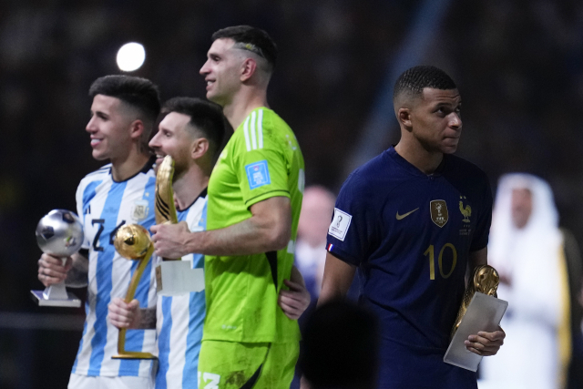 프랑스의 킬리안 음바페가 19일(한국 시간) 골든부트를 수상한 뒤 월드컵 트로피를 지나치고 있다. AP연합뉴스