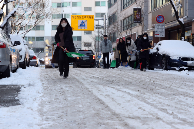 19일 오전 광주 서구 상무1동 주택가에서 공무원이 도로에 쌓인 눈을 치우고 있다.