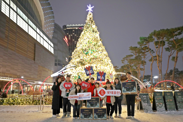 롯데물산 임직원들이 19일 롯데타워 앞 크리스마스트리에서 해피박스를 전달하기 전 기념 촬영을 하고 있다. /사진제공=롯데물산