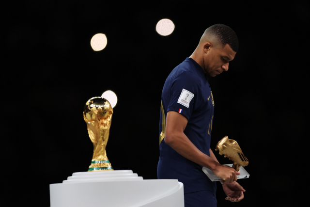 프랑스의 킬리안 음바페가 19일(한국 시간) 골든부트를 수상한 뒤 월드컵 트로피를 지나치고 있다. EPA연합뉴스