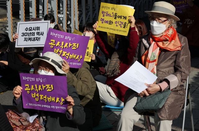 지난달 23일 서울 종로구 주한일본대사관 인근 평화로에서 열린 일본군 위안부 피해자 문제 해결을 위한 제1571차 정기수요시위에서 참가자들이 손팻말을 들고 있다. 연합뉴스