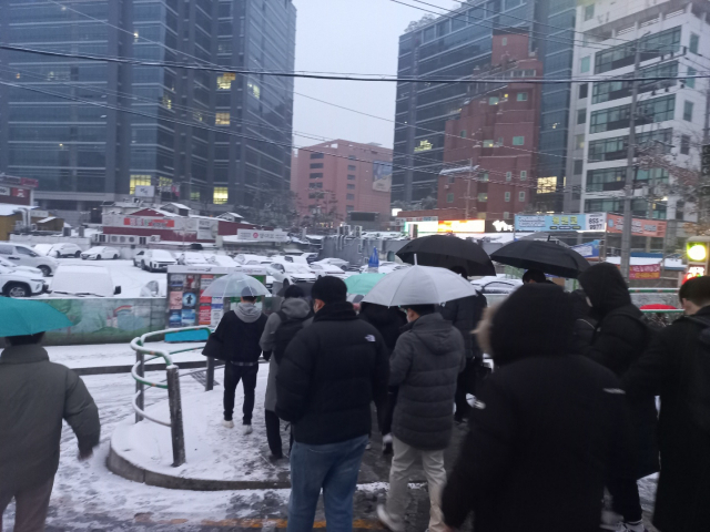대설특보가 발효된 21일 오전 시민들이 서울 영등포구에서 우산을 쓴 채 출근을 하고 있다. 이건율 기자