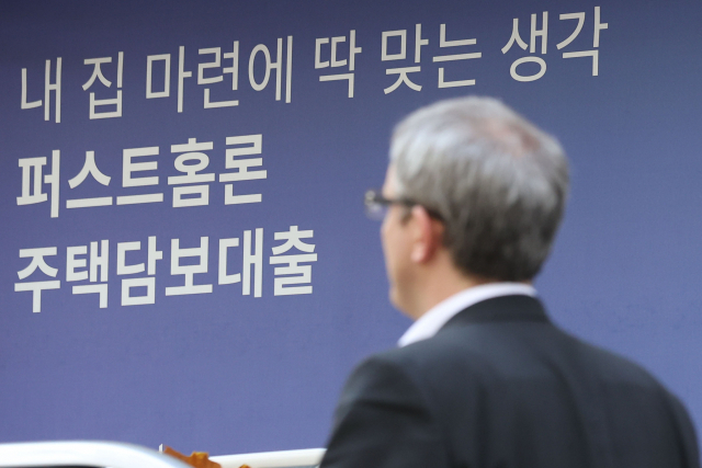 한 남성이 시중은행 벽에 붙은 대출 안내 현수막 앞을 지나가고 있다. 연합뉴스