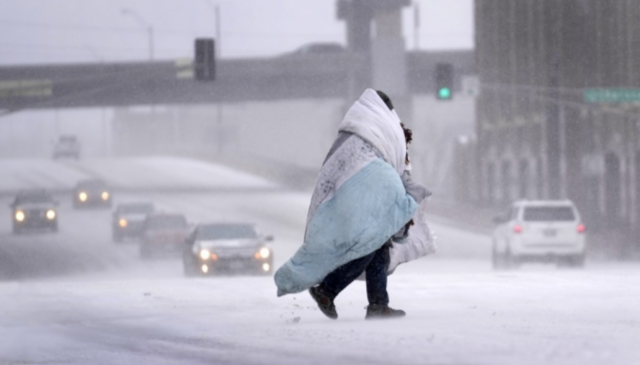 미국 세인트루이스에 눈이 내리는 가운데 한 시민이 담요를 두르고 길을 건너고 있다. AP연합뉴스