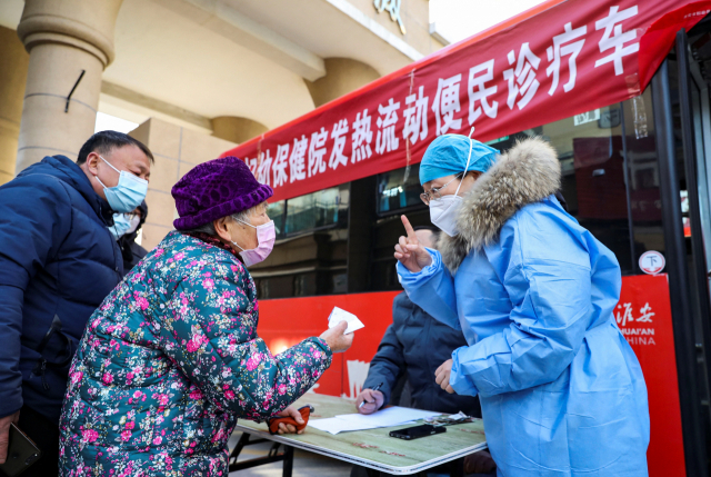 중국 장쑤성 화이안의 버스를 이동식 발열 클리닉으로 전환한 진료소에서 25일 의료진이 주민에게 코로나19 관련 지침을 전달하고 있다. 로이터연합.