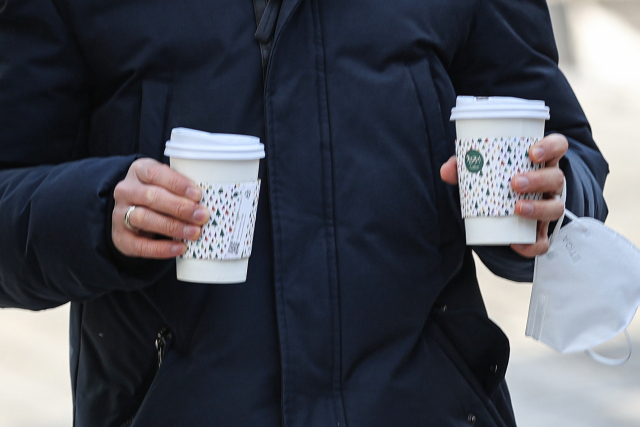 한 시민이 양손에 따듯한 커피를 들고 서울 명동거리를 걷고 있다. 연합뉴스
