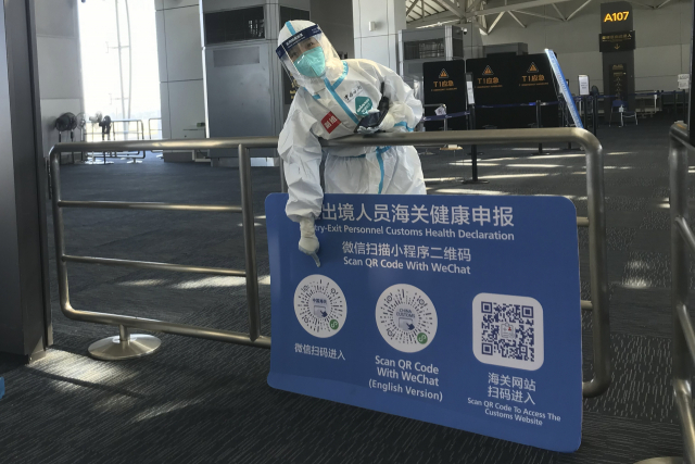 보호 장비를 착용한 한 근무자가 25일 중국 광둥성 광저우 바이윈 공항에 도착한 여행객들을 대상으로 건강 QR코드를 스캔하라며 가리키고 있다. 중국은 내년 1월 8일부터 이 같은 해외 입국 시 필요한 방역 조치를 철폐한다고 26일 밝혔다. AP연합