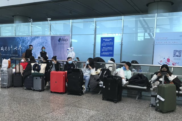 25일 중국 광둥성 광저우 바이윈 국제공항에 입국한 여행객들이 격리시설로 이동하는 버스를 타기 위해 대기하고 있다. 중국 방역 당국은 26일 코로나19 방역 차원에서 시행해온 해외 입국자 시설격리를 내년 1월 8일자로 폐지한다고 발표했다. AP연합뉴스