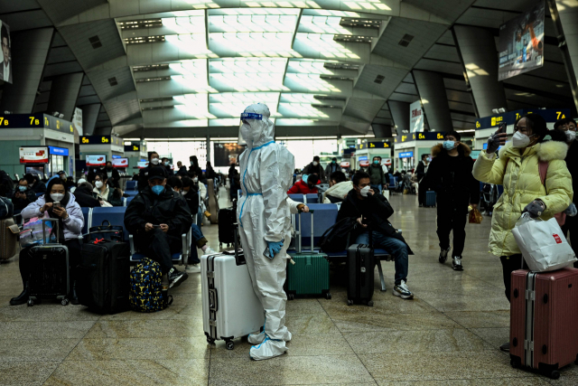 28일 중국 베이징 기차역에 한 승객이 방역복을 갖춰 입고 서있다. 연합뉴스