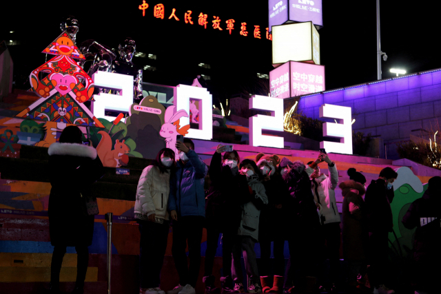 베이징의 한 쇼핑센터 앞에 모인 사람들이 지난달 31일 새해를 앞두고 2023년을 알리는 조형물과 함께 사진을 찍기 위해 포즈를 취하고 있다. 로이터연합뉴스