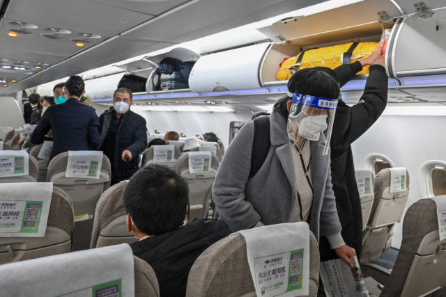 상하이 푸둥국제공항에서 3일 비행기에 탄 승객들이 안면 보호막과 마스크를 착용한 채 기내에 탑승하고 있다. AFP연합.
