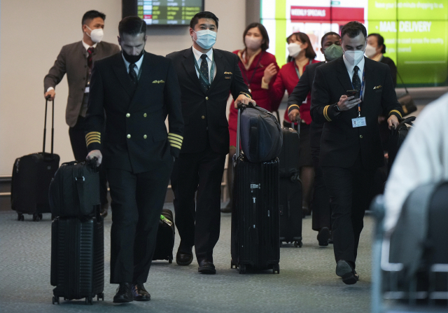 홍콩에서 캐나다 밴쿠버 국제공항에 도착한 캐세이퍼시픽항공사 직원들이 4일(현지 시간) 캐리어를 끌며 이동하고 있다. AP연합뉴스