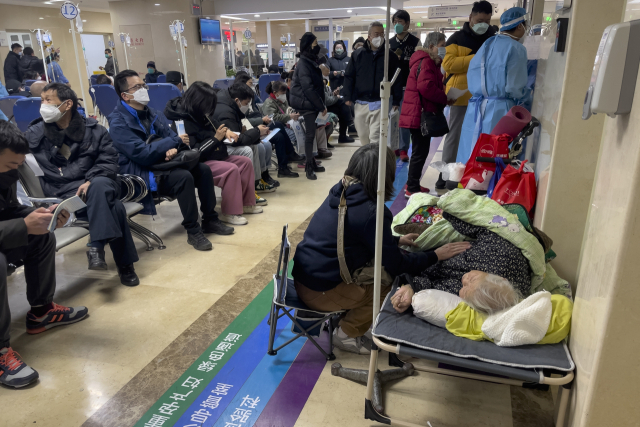 5일 중국 베이징의 한 병원 응급병동 복도에서 환자들이 정맥주사를 맞고 있는 가운데 한 여성이 들것에 누워있는 연로한 친척을 돌보고 있다. 노인들이 대부분인 환자들은 들것에 누워있는가하면 산소를 흡입하거나 휠체어에 앉아있다. AP연합뉴스