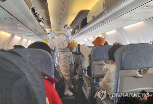 5일 중국으로 향하는 인천공항발 중국 항공사 여객기 안에서 승무원들이 방역복을 착용한 채 근무하고 있다. 연합뉴스