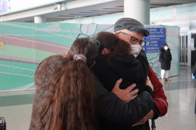 중국이 해외 입국자 격리를 폐지한 첫 날인 8일 베이징 셔우두 국제공항에서 2년 7개월여 만에 딸 리아나(가운데)씨를 만난 존씨 부부가 딸과 부둥켜 안고 있다. 김광수특파원.