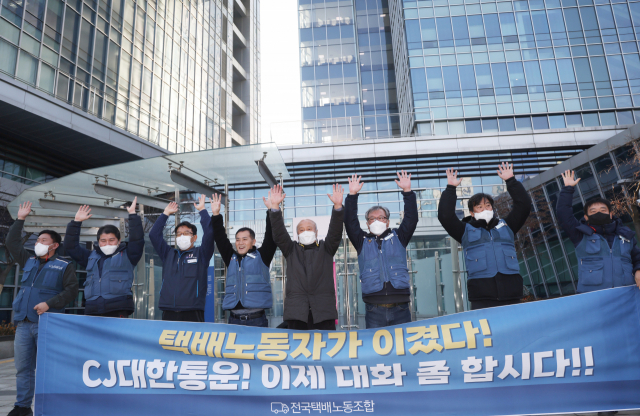 민주노총 전국택배노조 관계자들이 12일 서울행정법원 앞에서 법원 판결에 환호하며 두 손을 들어 보이고 있다. 연합뉴스