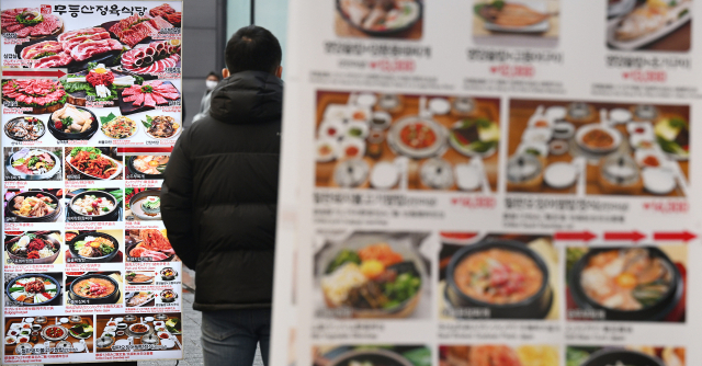 한국은행 금융통화위원회가 사상 처음으로 일곱 차례 연속 기준금리 인상을 결정한 13일 서울 중구 명동을 찾은 시민들이 음식 가격을 확인하고 있다. 금통위는 통화정책방향 회의 의결문에서 인상 배경에 대해 
