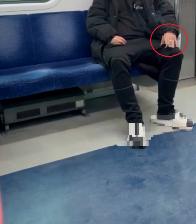 한 남성이 지하철 안에서 마스크를 내린 채 흡연하고 있다.