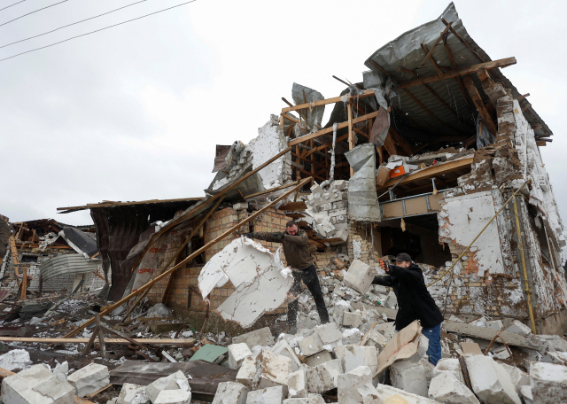 26일(현지 시간) 우크라이나 키이우 외곽 도시 흘레바하에서 주민들이 러시아군의 공격으로 무너진 이웃집의 잔해를 정리하고 있다. 로이터연합뉴스