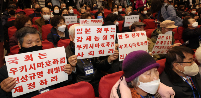 12일 오전 서울 여의도 국회 의원회관에서 열린 강제징용 해법 논의를 위한 공개토론회에서 참석자들이 피켓을 들고 있다. 연합뉴스