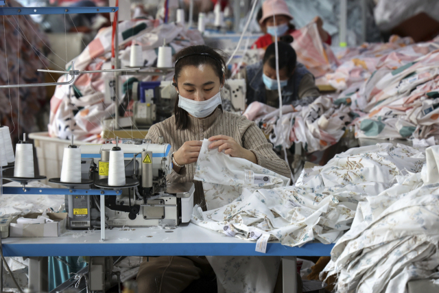 중국 동부 산둥성 후이민현의 한 섬유 공장에서 25일 마스크를 쓴 근로자들이 바느질을 하고 있다. AP연합뉴스.