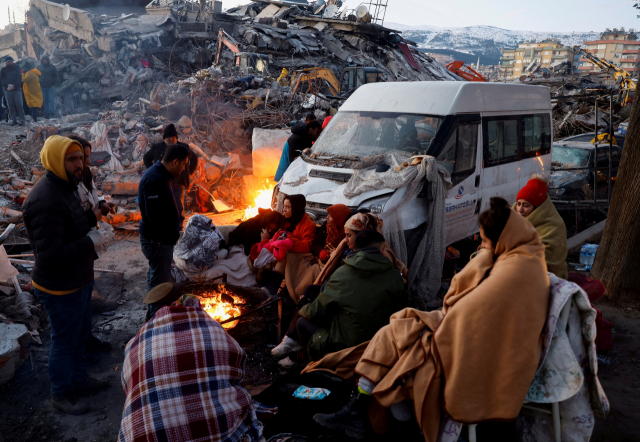 8일(현지시간) 튀르키예 남부 카흐라만마라슈시에서 지진 피해자들이 무너진 건물 잔해 옆에서 모닥불을 피워 몸을 녹이고 있다. 로이터연합뉴스