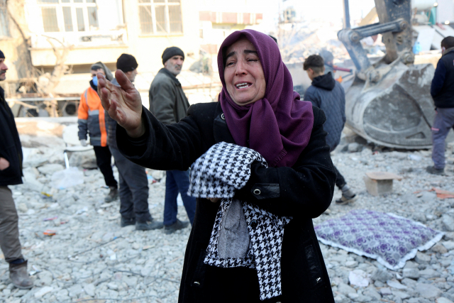 12일(현지시간) 튀르키예 남동부 도시 아디야만에서 주민 아딜레 이시크가 건물 잔해에 갇힌 그녀의 21살 아들이 구조되길 기다리고 있다. 로이터연합뉴스