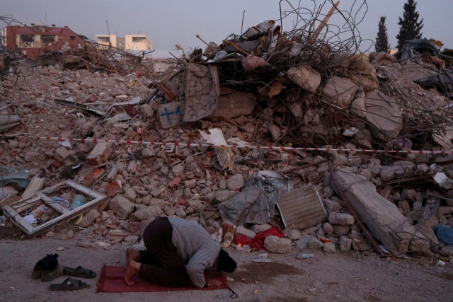 무너진 주택 잔해 옆에서 기도하는 튀르키예 남성의 모습. 로이터 연합뉴스