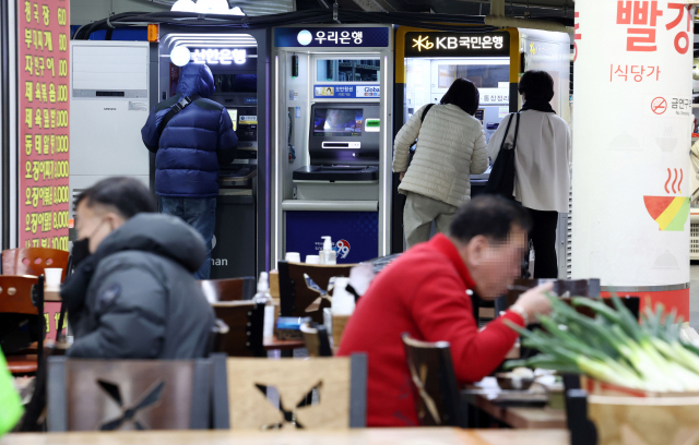시민들이 서울 시내의 한 시장 내 식당가 앞에 설치된 은행 현금인출기(ATM)를 이용하고 있다. 연합뉴스