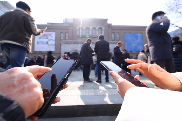17일 점심시간 서울 중구 서울시립미술관 앞에서 시민들이 휴대폰을 보고 있다. 연합뉴스