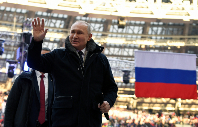 푸틴 러시아 대통령이 22일 러시아 모스크바 축구경기장에서 열린 러시아 군인들을 위한 콘서트에 서 인사하고 있다. 로이터 연합뉴스