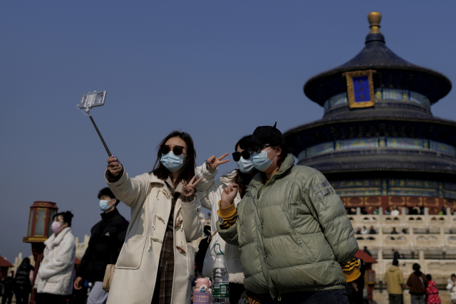 선글라스와 마스크를 착용한 여성들이 26일 베이징 톈탄공원에서 셀카를 찍고 있다. 중국 당국이 코로나19 방역 조치를 해제한 이후 중국 전역의 관광지에 인파가 몰려들고 있다. AP연합