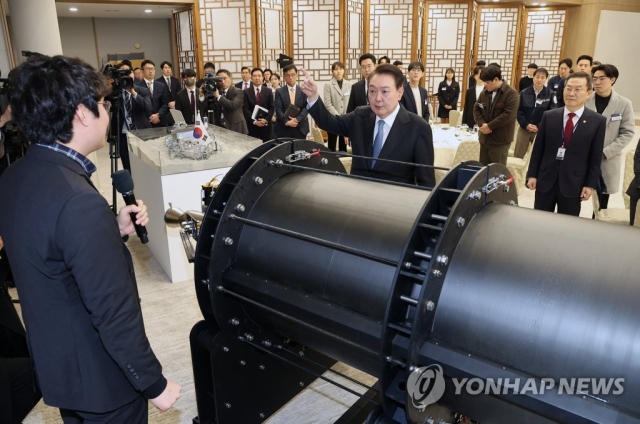 윤석열 대통령이 이달 21일 서울 용산 대통령실 청사에서 열린 '꿈과 도전의 뉴스페이스 시대, 우주경제 개척자와의 대화'에 앞서 소형 우주 발사체를 살펴보고 있다. 연합뉴스