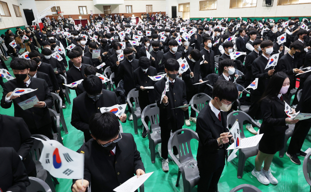 1일 오후 경기도 수원시 팔달구 삼일공업고등학교에서 열린 입학식 및 3·1절 기념식에서 신입생들이 태극기를 들고 3·1절 노래를 부르고 있다. 연합뉴스