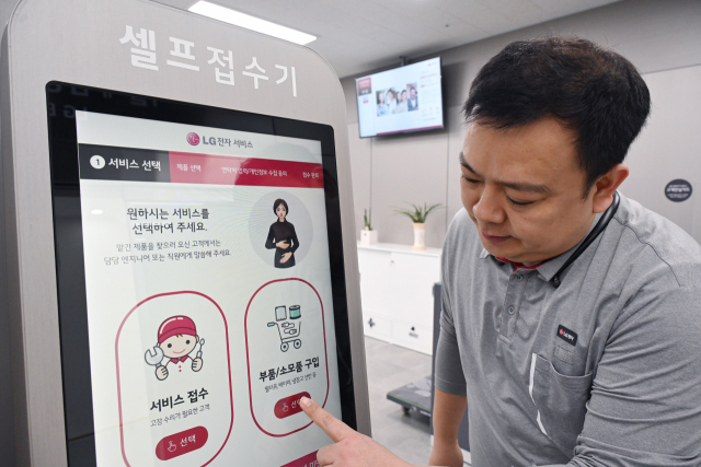 LG전자 서비스엔지니어가 서울 광진구에 위치한 LG전자 광진서비스센터에 설치된 키오스크에서 디지털휴먼의 수어 안내를 받아 서비스를 접수하는 방법을 안내하고 있다. 사진 제공=LG전자