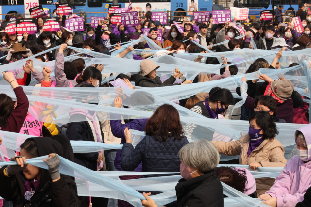 세계여성의날을 나흘 앞둔 지난 4일 서울 종로구 보신각 앞에서 여성노동연대회의가 주최한 2023 여성노동자대회에서 참가자들이 여성차별의 상징인 유리천장을 깨고 나가자는 의미로 투명한 천을 찢는 퍼포먼스를 하고 있다. 연합뉴스