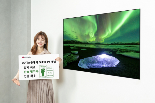 LG디스플레이 모델이 유기발광다이오드(OLED) TV 패널 앞에서 카본 트러스트 인증서를 들어 보이고 있다. 사진 제공=LG디스플레이