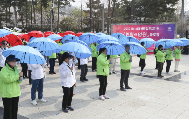 29일 오후 부산 남구 평화공원에서 구청 직원과 지역주민들이 2030부산세계박람회 유치 기원하며 스포츠타월 및 우산을 활용하여 퍼포먼스를 펼치고 있다./연합뉴스